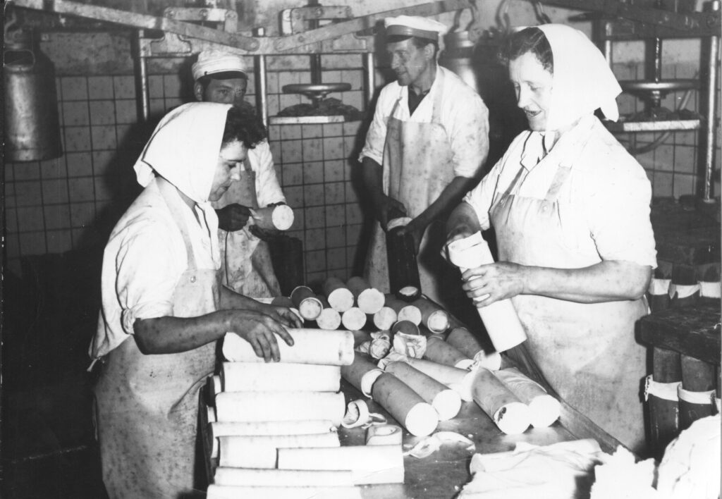 Stare czarno-białe zdjęcie pracowników robiących ser salami w zakładzie